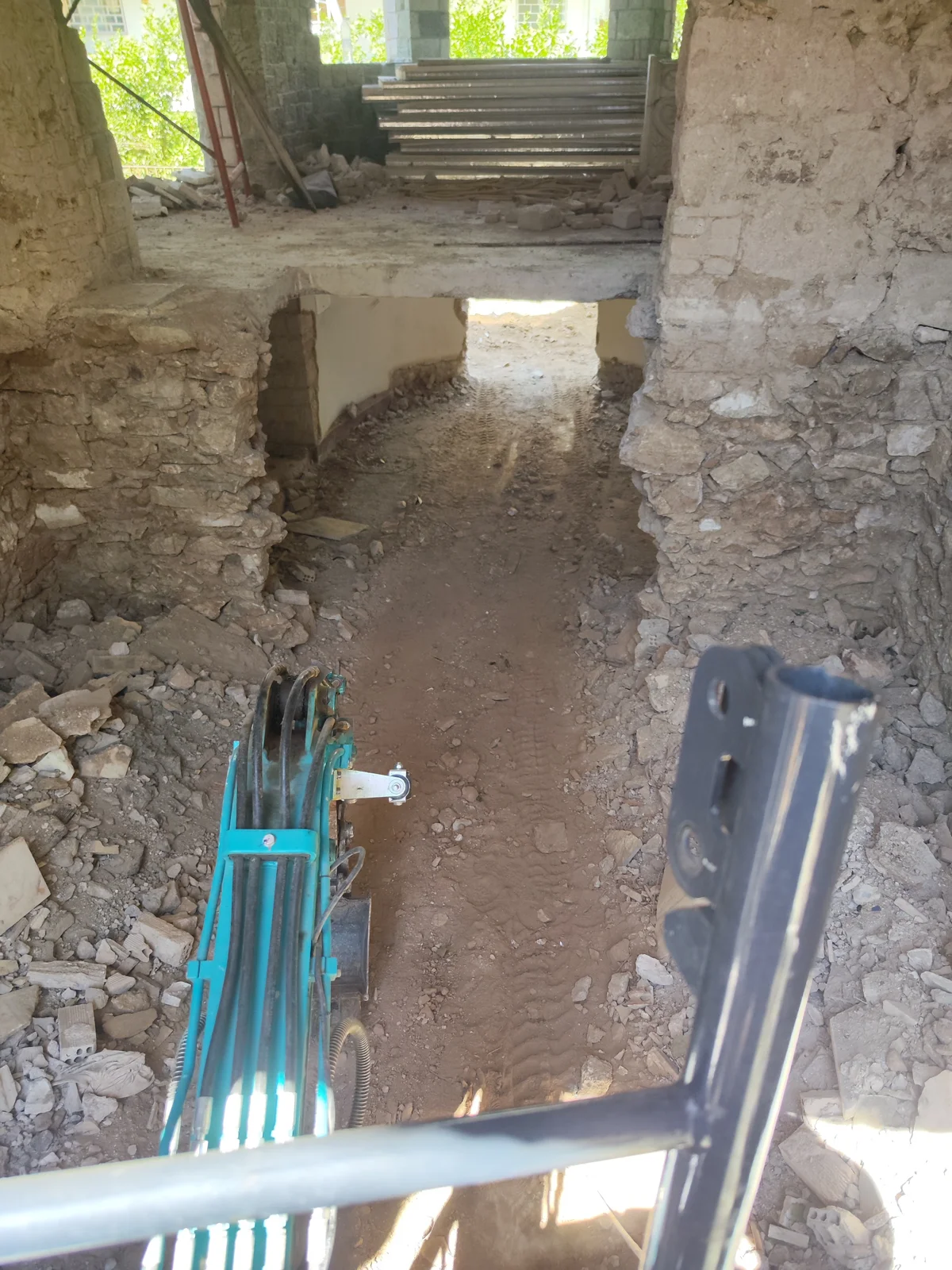Μικρός εκσκαφέας σε διαδρομή πρόσβασης μέσα από στενό και χαμηλό άνοιγμα οικοδομής