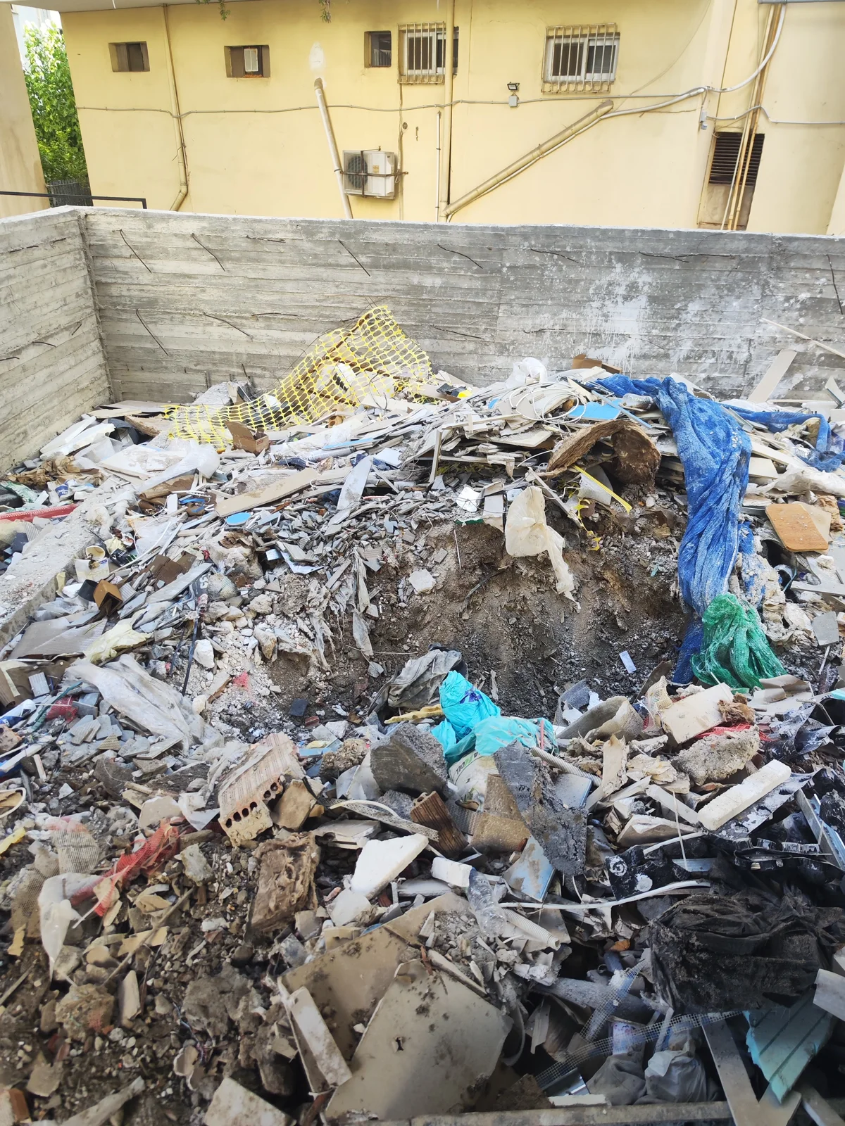 Ακάλυπτος οικοδομής με μπάζα και δομικά υπολείμματα πριν τον καθαρισμό